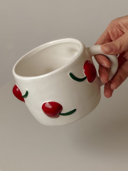 كوب سيراميك مع حبات كرز بارزة باللون الأحمر
