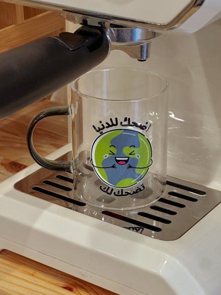 كوب شفاف بعبارة "اضحك للدنيا تضحلك"