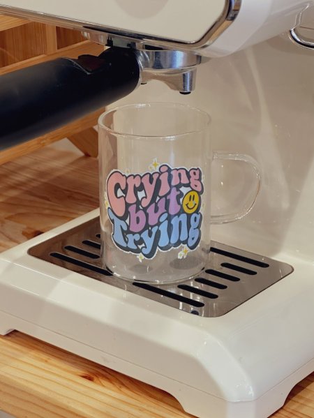 كوب شفاف بعبارة "crying but trying"