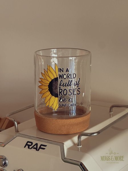 كوب بعبارة ”in a world full of roses be a sunflower “