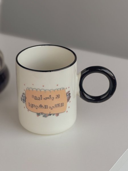 كوب بعبارة "لا بأس أيها القلب الشجاع"